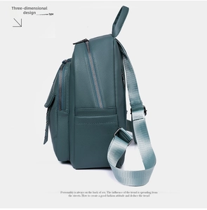 Side view of dark green pebbled leather backpack showing multi-layer silver zippers and rivets