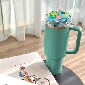Detail of 40oz green tumbler featuring a 3D frog and floral straw topper attachment