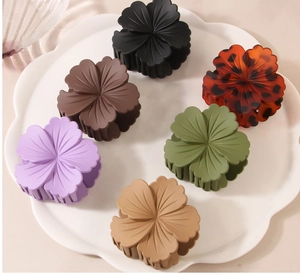 Close-up of matte flower claw clips in six colors displayed on a white wave tray