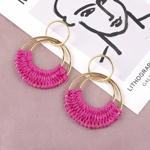 Detail view of pink hand-woven cotton thread with double gold metal rings earrings