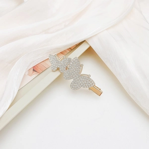 Detail of three golden butterfly hair clips with sparkling rhinestones on silk fabric