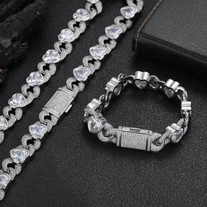 Macro-opname van zilveren Cubaanse schakelketting en armband set met hartvormige zirkoon
