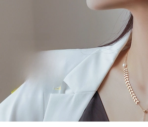 Detail of a vintage 18k gold wave ring with a white pearl on a model in a white suit