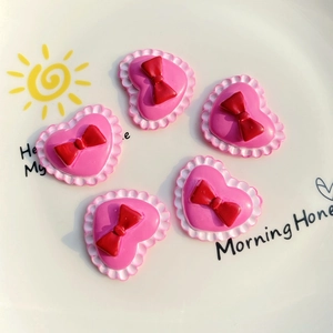 Detail shot of five resin heart charms with red bows for DIY phone case crafts
