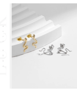 Macro detail of S925 sterling silver snake earrings in gold and silver finish with zircons