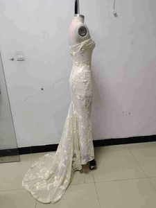 Detailed close-up of intricate floral lace patterns on white fishtail evening gown