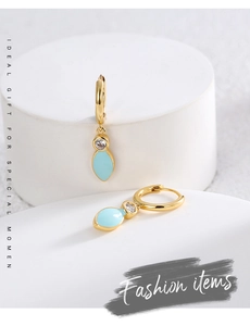 Detail view of gold hoop earrings with clear zircon and light blue leaf drop charms