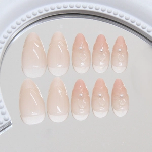 Faux ongles amande courts avec dégradé nude, perles élégantes et finition miroir