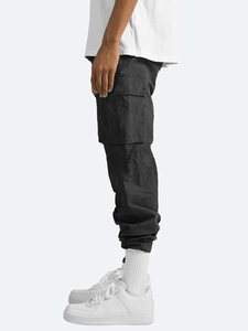 Detail of cargo pants with large side flap pockets and elastic cuffs on male model