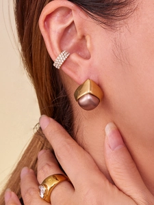 Detail view of geometric gold earrings with matte purple beads and zircon ring