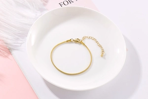 Detail of adjustable gold-plated snake bone chain with lobster clasp and ball charm