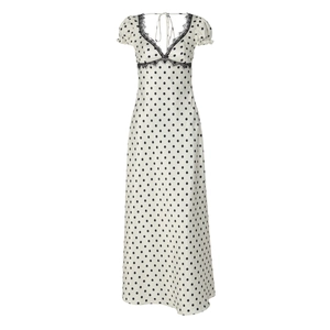 Dettaglio di un abito bianco a pois con scollo a V, pizzo nero e laccio sul retro