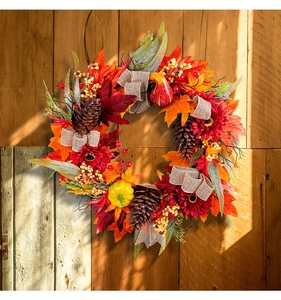 Detailed view of autumn wreath with maple leaves, sunflowers, pine cones, and pumpkins.