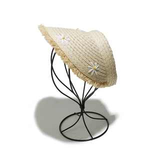 Detail of straw sun visor with white daisy ornaments and trendy frayed tassel edges