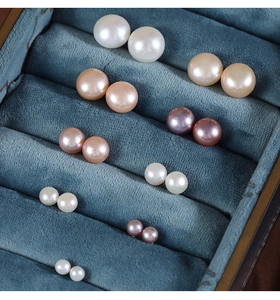 Macro shot of multi-colored freshwater pearl earrings in a luxury teal velvet box