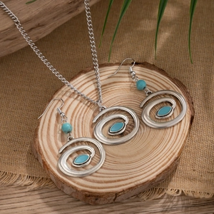 Detail of silver spiral necklace and earrings set with turquoise stones on wood