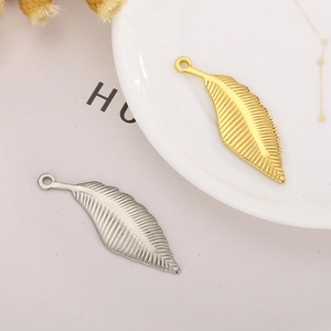 Detail of gold and silver stainless steel leaf pendants with rings on white tray
