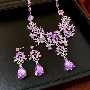 Detail of silver floral jewelry set with purple gemstones and teardrop pendants in a box