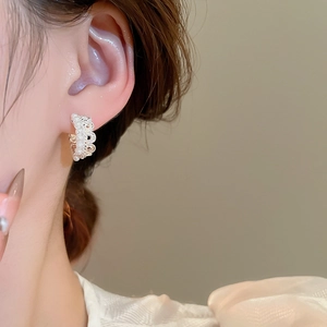Close-up of elegant crown lace pearl hoop earring worn by model in soft warm lighting