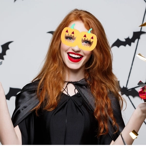 Detail of Halloween costume set with smiling orange pumpkin glasses and black satin cloak