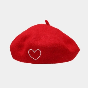 Close-up of red wool beret featuring a minimalist white heart embroidery detail
