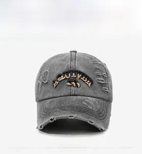 Detail of grey washed denim baseball cap featuring distressed holes and 3D letter embroidery