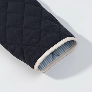 Detail of navy quilted jacket cuff with beige trim and blue striped lining fabric