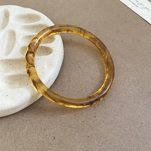 Macro view of vintage amber resin bangle featuring artistic tortoiseshell patterns and textures
