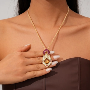 Gros plan du pendentif doré vintage avec ambre et pierre violette sur un mannequin
