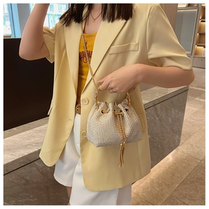 Close-up of sparkling rhinestone bucket bag with golden chain and tassel drawstring detail