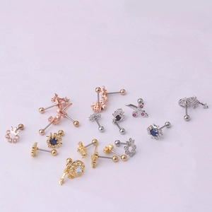 Set of stainless steel cartilage piercings with moon, star, and crown motifs on pink background