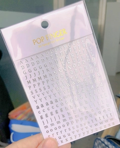 Detailed view of silver 3D nail art stickers with uppercase and lowercase letters