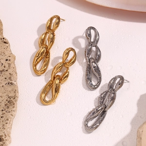Detail of gold and silver irregular triple-link chain earrings with lava texture surface