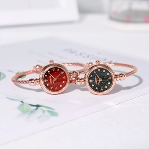Close-up of elegant women's rose gold bangle quartz watches with red and black dials