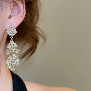 Close-up of silver hollow floral tassel earrings with intricate vintage floral carving