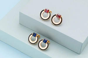 Detailansicht geometrischer Ohrringe mit roten und blauen Kristallen in Goldfassung