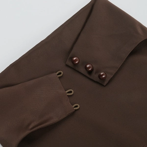 Close-up of deep brown dress fabric featuring three spherical buttons and elastic loop closures