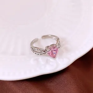 Elegant silver open ring with pink heart zircon and hollow geometric band on a ceramic dish