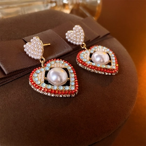 Vue macro de boucles d'oreilles cœur en perles et strass colorés sur du velours