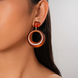 Vue détaillée des boucles d'oreilles créoles en résine ambre portées par un mannequin chic