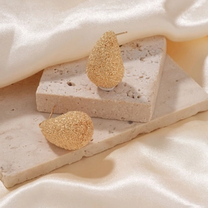 Elegant gold teardrop earrings with textured sand finish on natural stone base