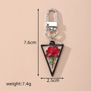 Detail of triangle dried flower keychain with red rose petals and silver metal clasp