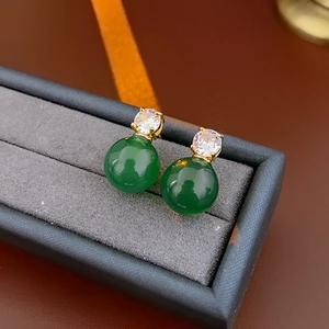 Détail de pierres vertes rondes et de zircones claires sur boucles d'oreilles