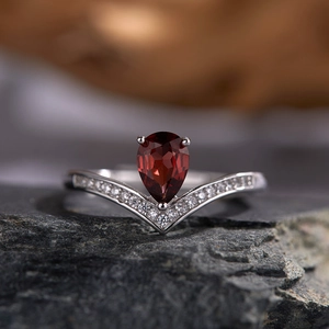 Macro shot of V-shaped silver ring with pear-cut garnet and sparkling side diamonds