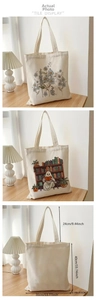Detail of white canvas tote bag with ghost reading and floral patterns and size dimensions