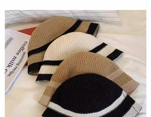 Top view of knitted bucket hats in beige, black, brown and camel with stripe details