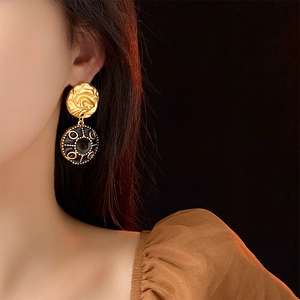 Detailed side view of a model wearing vintage round gold and black oil-drop earrings
