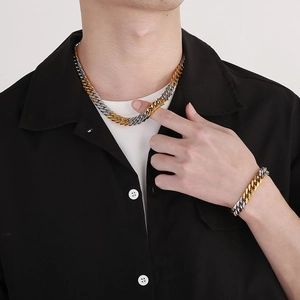 Detail view of two-tone gold and silver interlocking Cuban chain necklace and bracelet
