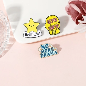 Three colorful enamel pins with motivational quotes and star motifs on a ceramic plate