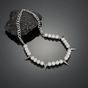Detailed close-up of hip hop pearl and steel chain necklace with silver cone spikes